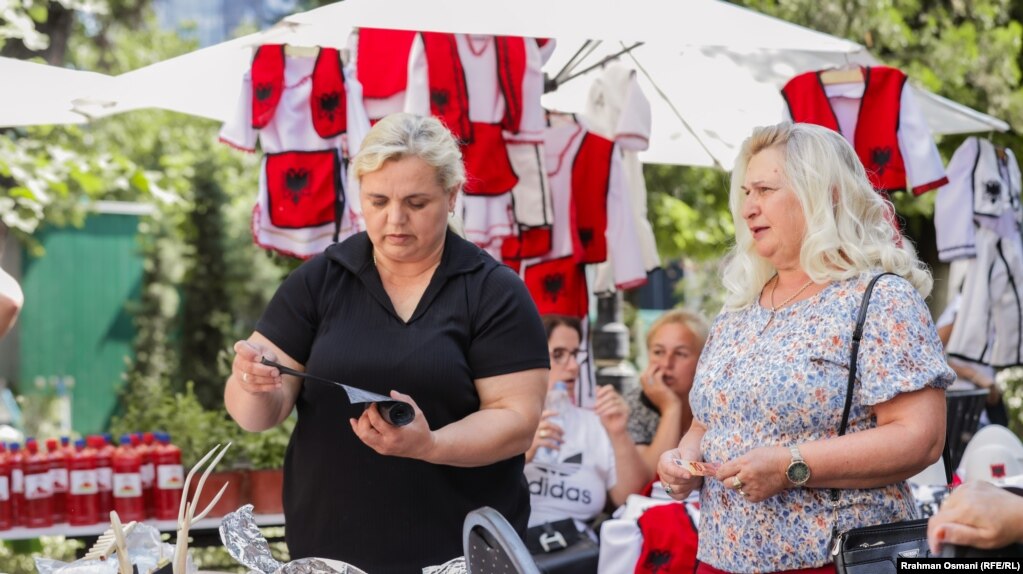 Afërdita Selimi-Jonuzi (majtas) nga Podujeva ishte njëra nga pjesëmarrëset që shiste ushqime tradicionale. Ajo tha se puna i shtohet dukshëm gjatë verës. “Mërgimtarët porosisin më së shumti fli dhe pite me kungull”, deklaroi ajo.