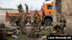 Garrett (középen) és az ukrán rendőrség tűzszerészegységének tagjai tüzérségi lövedékeket rakodnak egy teherautóra a Kijevtől északra fekvő Bucsában április 28-án