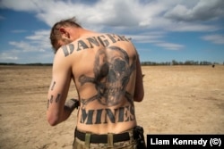 Garrett egy meleg tavaszi napon Kijevtől északra április 28-án. A hátán lévő hatalmas tetováláson ez áll: Veszély, aknák!