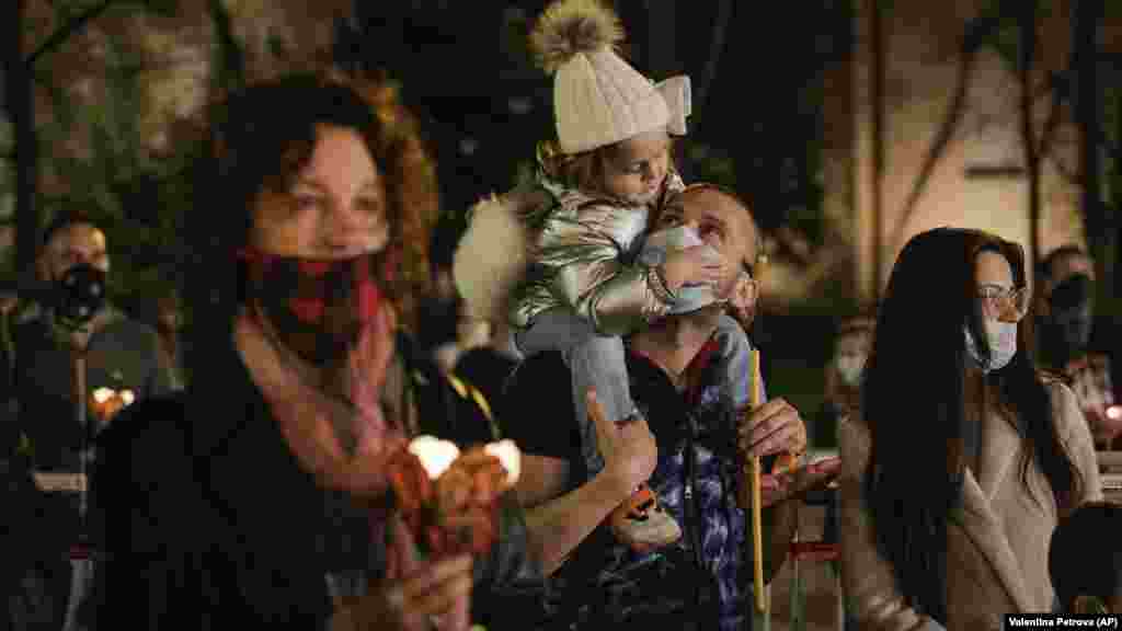 Father carries his daughter as they attend midnight Easter Orthodox Mass in front of Alexander Nevsky Cathedral in Sofia, Bulgaria, on April 19. The Bulgarian Orthodox Church resisted calls to close churches for Easter, the most significant holiday in the Orthodox calendar. But following demands by health authorities, it urged worshipers to pray at home rather than going to church.&nbsp;