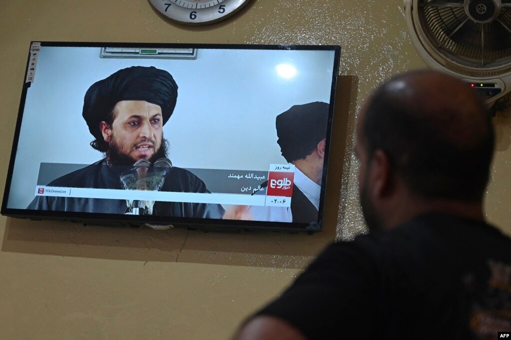 An Afghan man at a Kabul restaurant watches a live television broadcast of the Tolo News channel showing a religious scholar speaking.