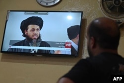 An Afghan man at a Kabul restaurant watches a live television broadcast of the Tolo News channel showing a religious scholar speaking.