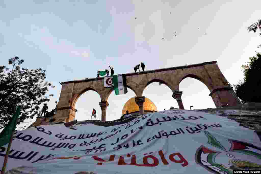 Palestinians hang a giant banner during Eid al-Fitr prayers marking the end of Ramadan on the compound known to Muslims as the Noble Sanctuary and to Jews as Temple Mount in Jerusalem&#39;s Old City on May 2.&nbsp;