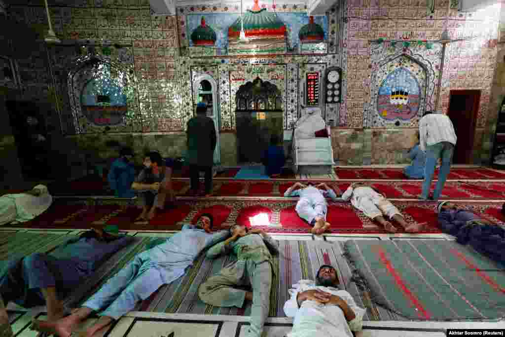 Burrat duke pushuar nga moti i nxehtë në dyshemenë e një xhamie në Karaçi të Pakistanit.