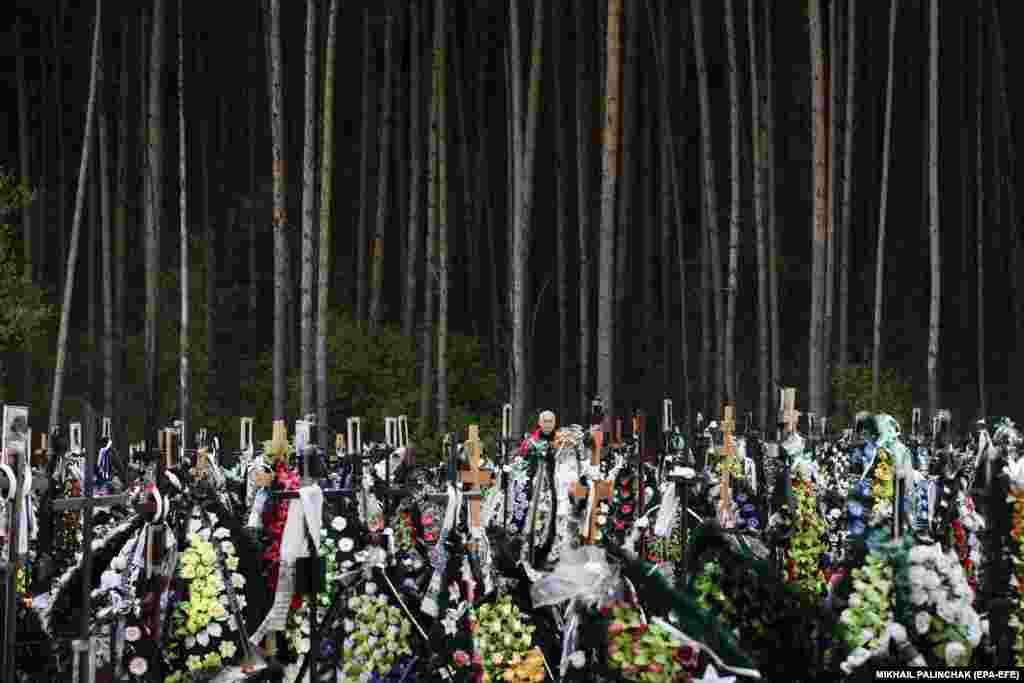 People mourn beside graves in a cemetery in Irpin, Ukraine.&nbsp;