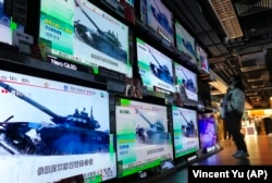 A woman in Hong Kong in front of TV screens showing the news that Russian troops invaded Ukraine on February 24.