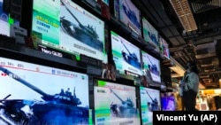 A woman in Hong Kong stands in front of TV screens showing the news that Russian troops invaded Ukraine on February 24.