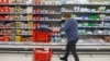 Russia - A customer shops for dairy at an Auchan hypermarket in Novosibirsk, April 7, 2022.