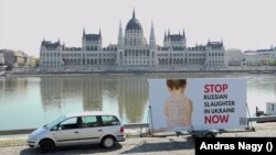 Egy lengyel plakát az ukrajnai orosz mészárlás leállítására szólít fel a magyar Parlamenttel szemben 2022 májusában