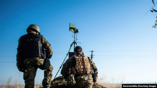 Украински военни тренират с дронове преди началото на руската инвазия в Украйна, 2022 г. Те наблюдават екран, показващ видео в реално време от октокоптер, докато предавател, монтиран на статив, комуникира с дрона.
