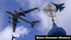 Un bombardier strategic Tu-95ms și un avion d eluptă Su-35S zboarăî în formație deasupre unei biserici la o repetiție pentru parada de 9, Moscova 4 mai 2022. 