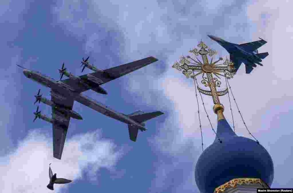 A Russian Su-35S combat aircraft and a Tu-95ms strategic bomber fly in formation above a church during a rehearsal on May 4 for the military parade marking the anniversary of the victory over Nazi Germany in World War II in Moscow.