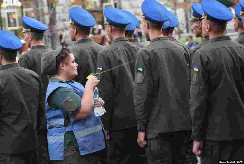 &nbsp;A military nurse in Kyiv sprays Ukrainian servicemen with water to cool them down from the heat during a rehearsal ahead of Independence Day celebrations on August 24. (AFP/Sergei Supinsky)