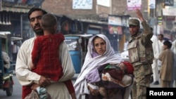 A family walks past a soldier on a street in Mingora, in Swat, on May 20.