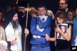 The parents of Ema Kobiljski, 13, mourn during the funeral procession at the central cemetery in Belgrade on May 6, 2023. She was one of eight students and a guard shot by schoolmate K.K.