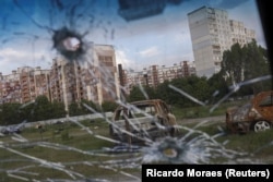 Burnt cars are pictured through the glass of a damaged car in the Saltivka neighborhood on May 10.