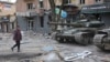 Një banor i Mariupolit kalon pranë tankeve të përdorura nga forcat separatiste pro-ruse, maj 2022.