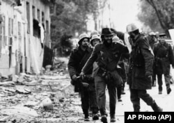 Soldiers from the Yugoslav People's Army advance through a street in downtown Vukovar during fighting on November 17, 1991.