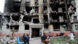 Місцеві жителі зібралися біля зруйнованого житлового будинку в Маріуполі, квітень 2022 року