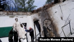 Zaposleni uklanjaju statuu ukrajinskog filozofa Hrihorija Skovorode nakon što je rusko bombardiranje pogodilo Književno-memorijalni muzej Hrihorij Skovoroda, 7. maj 2022. 