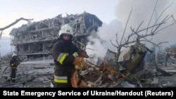 Emergency personnel -- one of them holding a rescued dog -- work near a building damaged after a Russian military strike in Odesa.