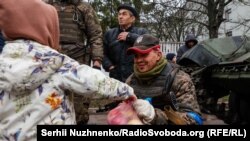 Чернігів. Дитина пригощає яблуками бійця тероборони. Початок квітня 2022 року