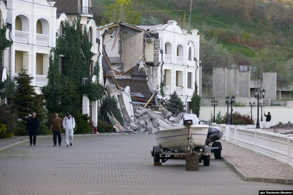 Njerëzit duke kaluar pranë një kompleksi hotelesh të shkatërruara nga një raketë ruse më 8 maj.