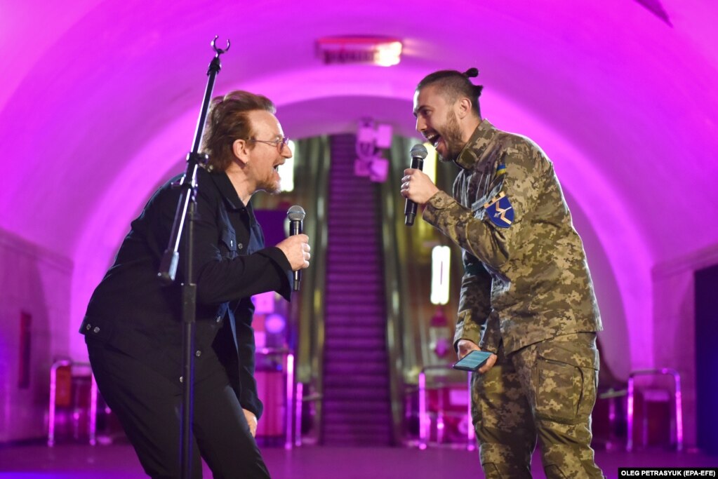 Muzikanti irlandez Bono (majtas) i grupit U2, duke performuar në stacionin e metrosë në Kiev, bashkë me këngëtarin ukrainas, Taras Topolya nga grupi Antytila, i cili tani shërben në ushtrinë ukrainase - 8 maj 2022.