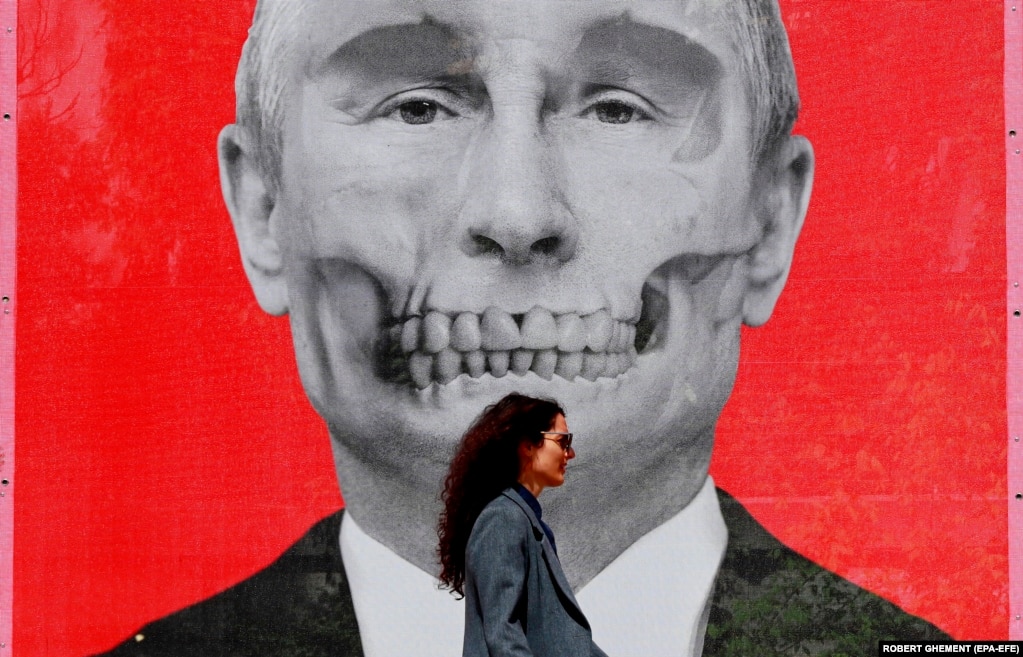 Një grua në Rumani duke ecur para një pllakati që shfaq Putinin skelet, afër Ambasadës së Rusisë, në Bukuresht, më 29 prill. Operacioni i Posaçëm Artistik është emri i një ekspozite të artit rrugor, ku janë shfaqur veprat e artistëve ukrainas dhe rumunë.