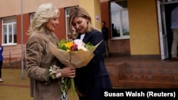 U.S. first lady Jill Biden (left) receives flowers from Olena Zelenska, wife of Ukraine's President Volodymyr Zelenskiy, outside a public school in Uzhhorod, Ukraine, on May 8.