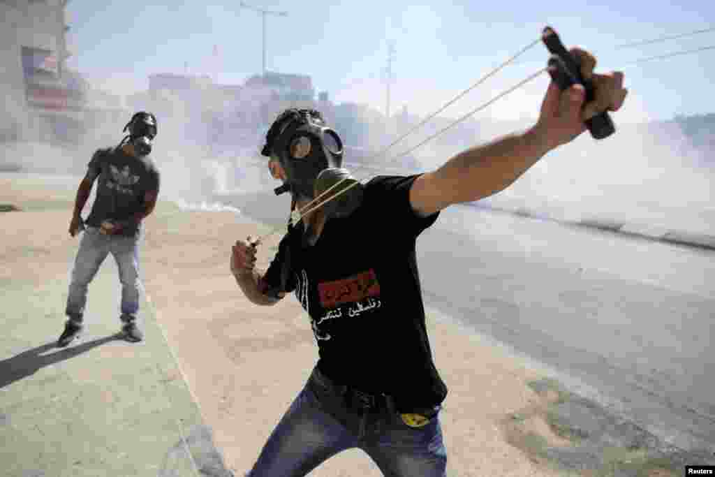 A Palestinian protester uses a slingshot to fire a stone at Israeli troops during clashes at a protest against the Israeli offensive in Gaza, in the West Bank town of Bethlehem. (Reuters/Ammar Awad)