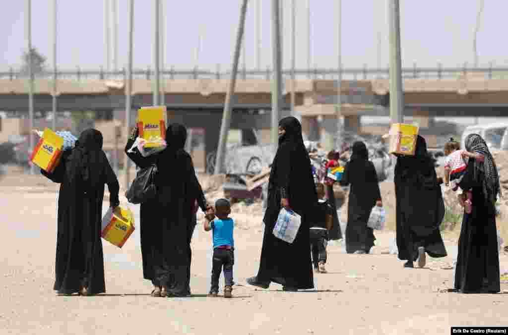 Displaced Iraqi residents carry boxes of biscuits and bottles of water given by an aid organization during the first day of the Eid-al Fitr celebration in west Mosul.