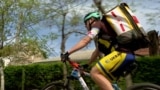 Volunteer riding a bicycle with Red Cross backpack in Mykolaiv