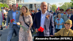 Fostul președinte Igor Dodon și deputatul socialist Vlad Bătrâncea, purtând „panglica Sf. Gheorghe” la un marș comemorativ pe 9 mai 2022, la Chișinău. Fosta primă doamnă, Galina Dodon, a venit la marș cu garoafe roșii.