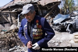 Second World War veteran Ivan Lisun, 97, wears a jacket with his medals and pins outside his house, which was damaged after a Russian bombardment, in Zolochiv, near Kharkiv.