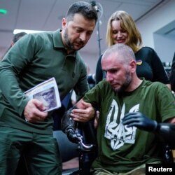 Președintele ucrainean Volodimir Zelenski ajută un soldat rănit să se ridice în timp ce îi acordă o medalie, cu ocazia vizitei la spitalul universitar Staten Island, New York, SUA, 18 septembrie 2023.