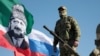 Грозный, военнослужащий на фоне флага с изображением Ахмата Кадырова и государственного флага России, 29 марта 2022 г. 