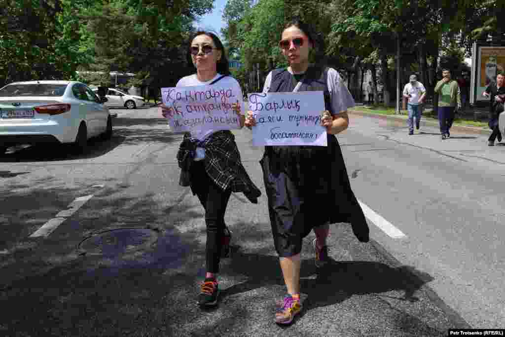 Активистки Жанель Шахан и Асем Жапишева с плакатами в руках направляются к сцене, где проходит концерт в честь Дня защитника Отечества. Девушки требовали справедливого расследования январских событий