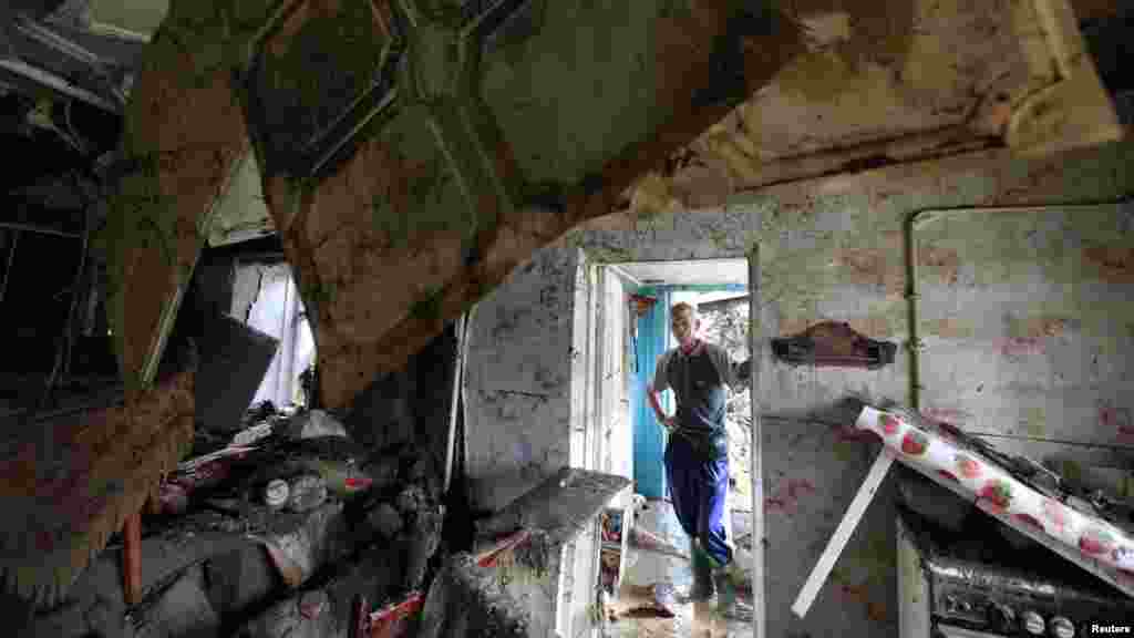 A local resident looks at the debris of a house damaged by floods in the town of Krymsk.