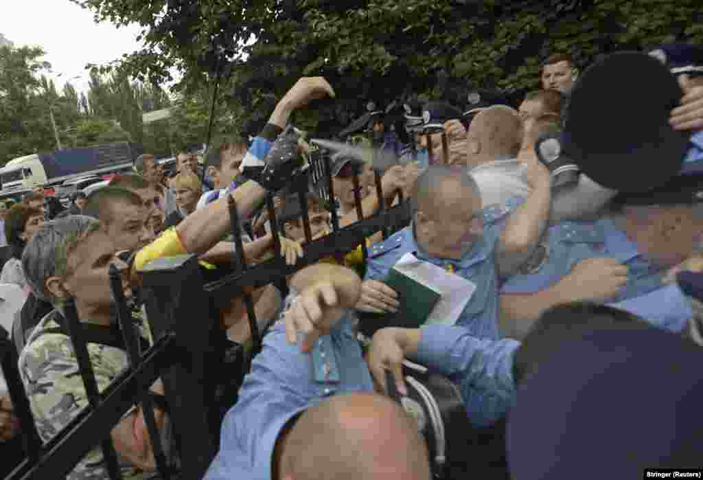 A protester sprays tear gas at police officers as angry residents attempt to storm the local police station in Kyiv. (Reuters)