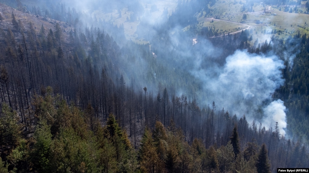 Pamje të malit të djegur derisa një zjarr i vogël vazhdon të djegë drunjtë e tjerë. 