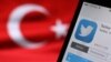 Turkey -- The logo of Twitter is seen on a smartphone held besides a Turkish flag - generic, 21 March 2014.