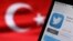 Turkey -- The logo of Twitter is seen on a smartphone held besides a Turkish flag - generic, 21 March 2014.