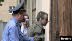 A participant in a flash mob is led into a Minsk court by a policeman 