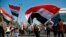 Students and other demonstrators hold national flags during a protest to condemn a pro-Iran militia attack on Najaf protesters, in Tahrir Square, Baghdad, Iraq, Thursday, Feb. 6, 2020. I
