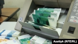 Банкноты номиналом пять тысяч, 10 и 100 кыргызских сомов.