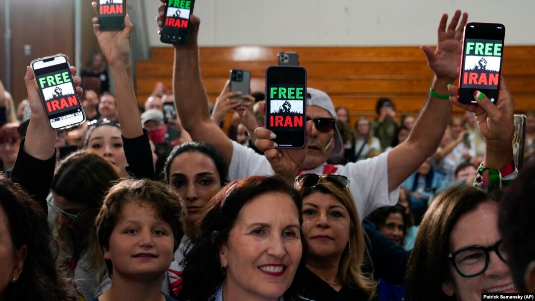 People hold up phones displaying the words "Free Iran" as President Joe Biden addresses a crowd in San Diego on November 3.