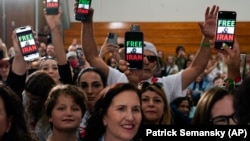 People hold up phones displaying the words "Free Iran" as President Joe Biden addresses a crowd in San Diego on November 3.