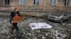 A local resident walks past the covered body of a person killed by recent shelling near a damaged block of apartments in Makiyivka in eastern Ukraine on November 4.