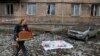 Žena prolazi pored pokrivenog tela osobe ubijene u nedavnom granatiranju u blizini oštećenog stambenog bloka u Makijevki u istočnoj Ukrajini 4. novembra
